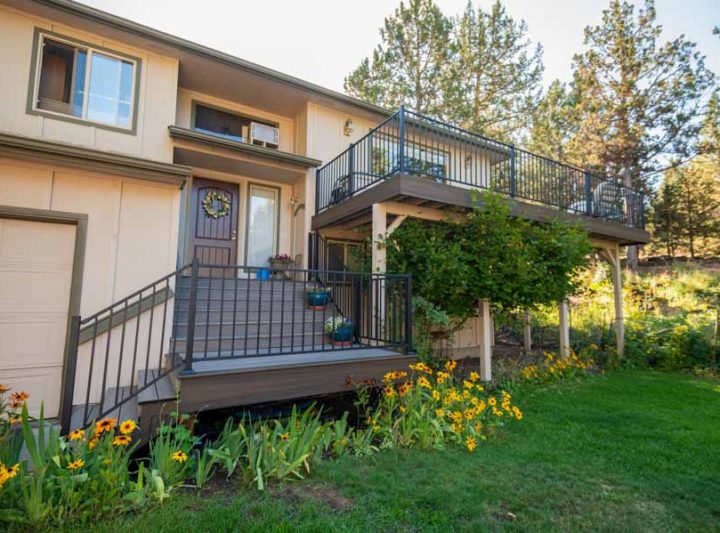 Residential balcony with decking and railing adorned with flowers, providing a picturesque and inviting outdoor space in a lush garden setting.