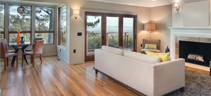 An inviting living and dining area with large windows providing a breathtaking view, featuring wooden floors, contemporary furniture, and subtle decor accents.