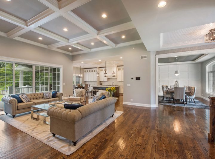 Luxurious open plan living area with large sofas, coffered ceilings, and a seamless connection to the kitchen and dining areas, enhanced by abundant natural light.