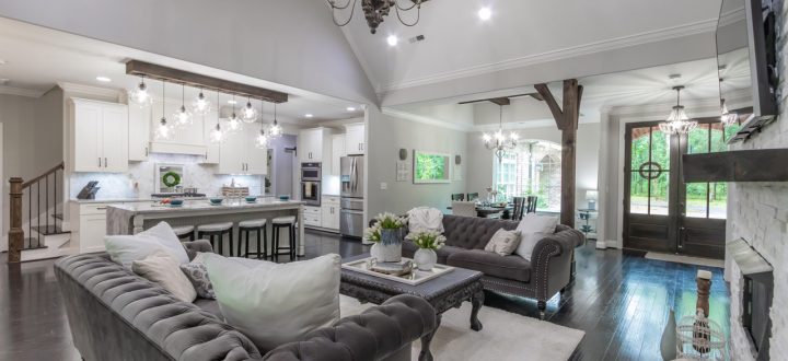 Spacious open plan living room connected to the kitchen featuring modern decor and lighting, with large windows overlooking the outdoor area.